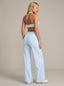 Woman wearing a light blue sports bra and high-waisted pants on a beige background