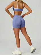 Person wearing a purple sports bra and shorts set on a gray background